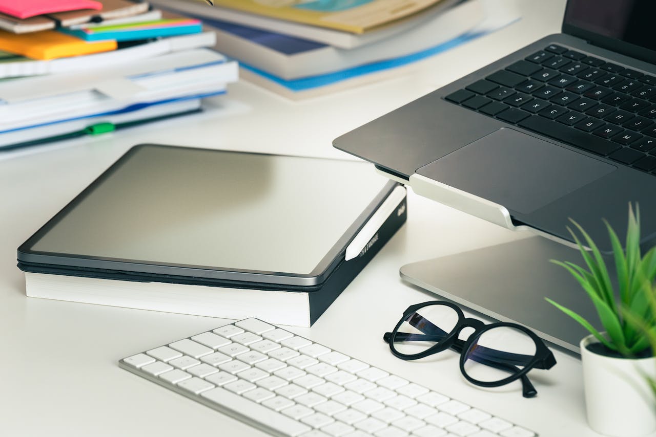 The Art of Drawing Readers In: Your attractive post title goes here A sleek office setup featuring a laptop, tablet, eyeglasses, and keyboard on a tidy desk.